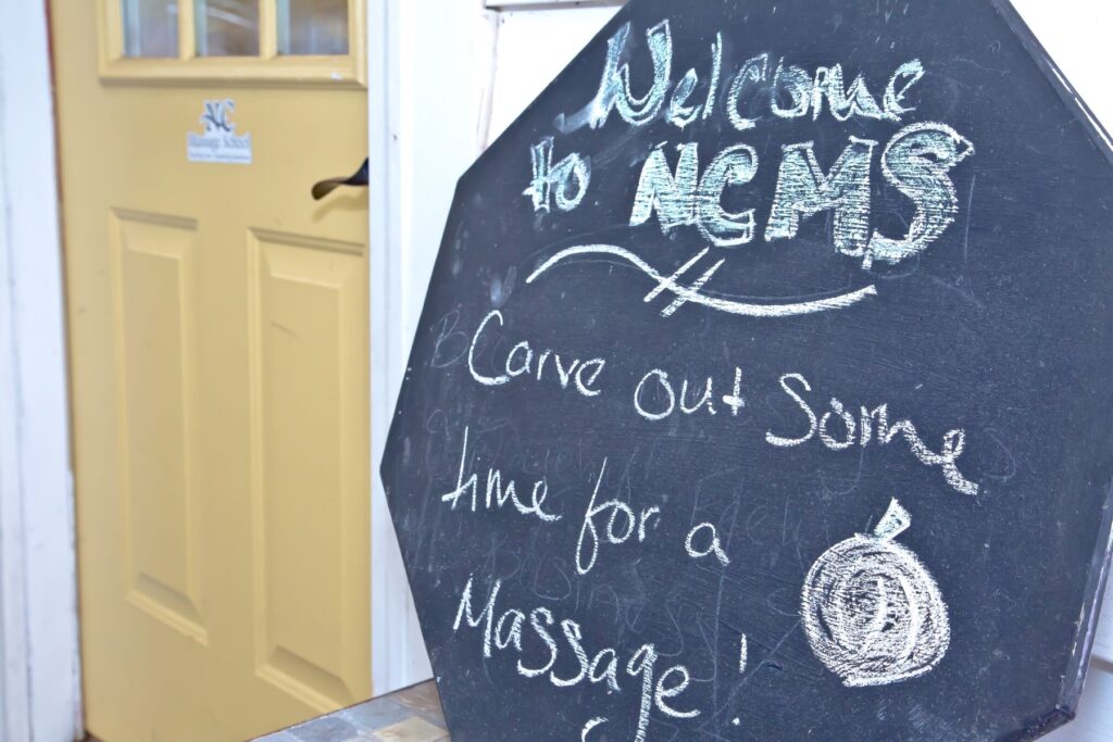 Chalkboard sign at the school entrance reading Welcome to NCMS, carve out some time for a massage